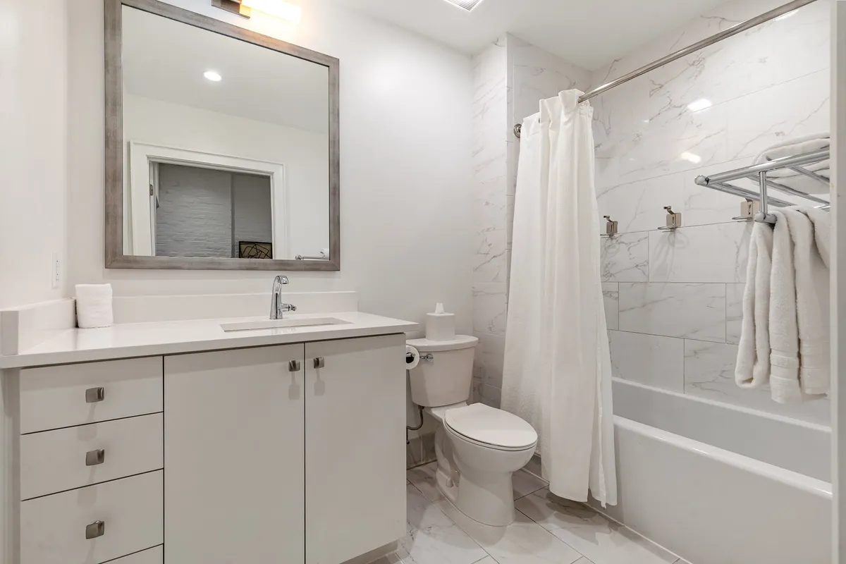 A modern bathroom with a large mirror above the sink and a bathtub, presented in a clean, bright, and calming style.